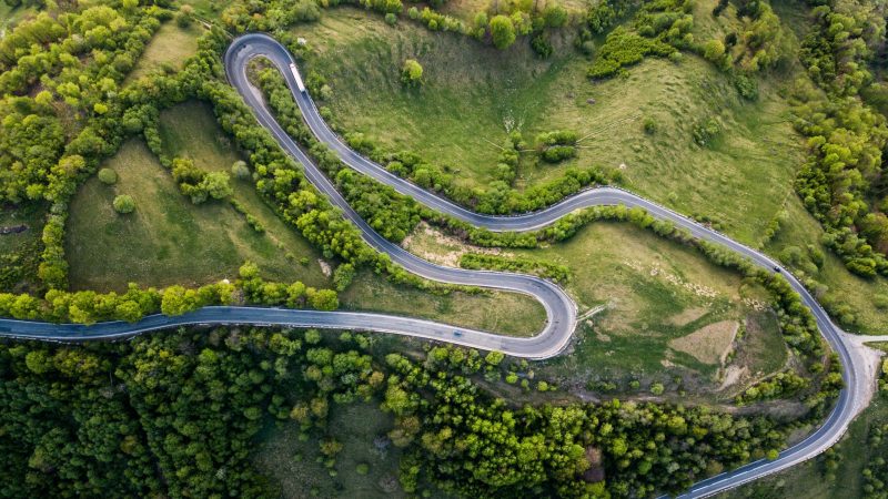 Beautiful aerial view of winding roadmountain cutting through forest landscape in summer time. Aerial view by drone . Romania